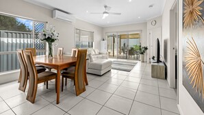 A modern living room with a dining area, featuring a wooden dining table, white sofas, and a ceiling fan. - "Poolside Escape in Scarborough" (Scarborough)