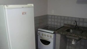 A compact kitchen with a white refrigerator, a stove, and a sink. - Praia Apart Hotel (Natal)