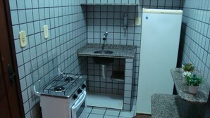 A compact kitchen with a gas stove, sink, and a small refrigerator. - Praia Apart Hotel (Natal)