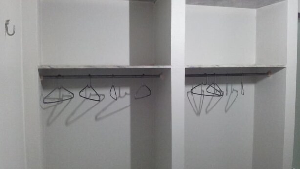A room with a white wall and a metal rack with clothes hangers. - Praia Apart Hotel (Natal)