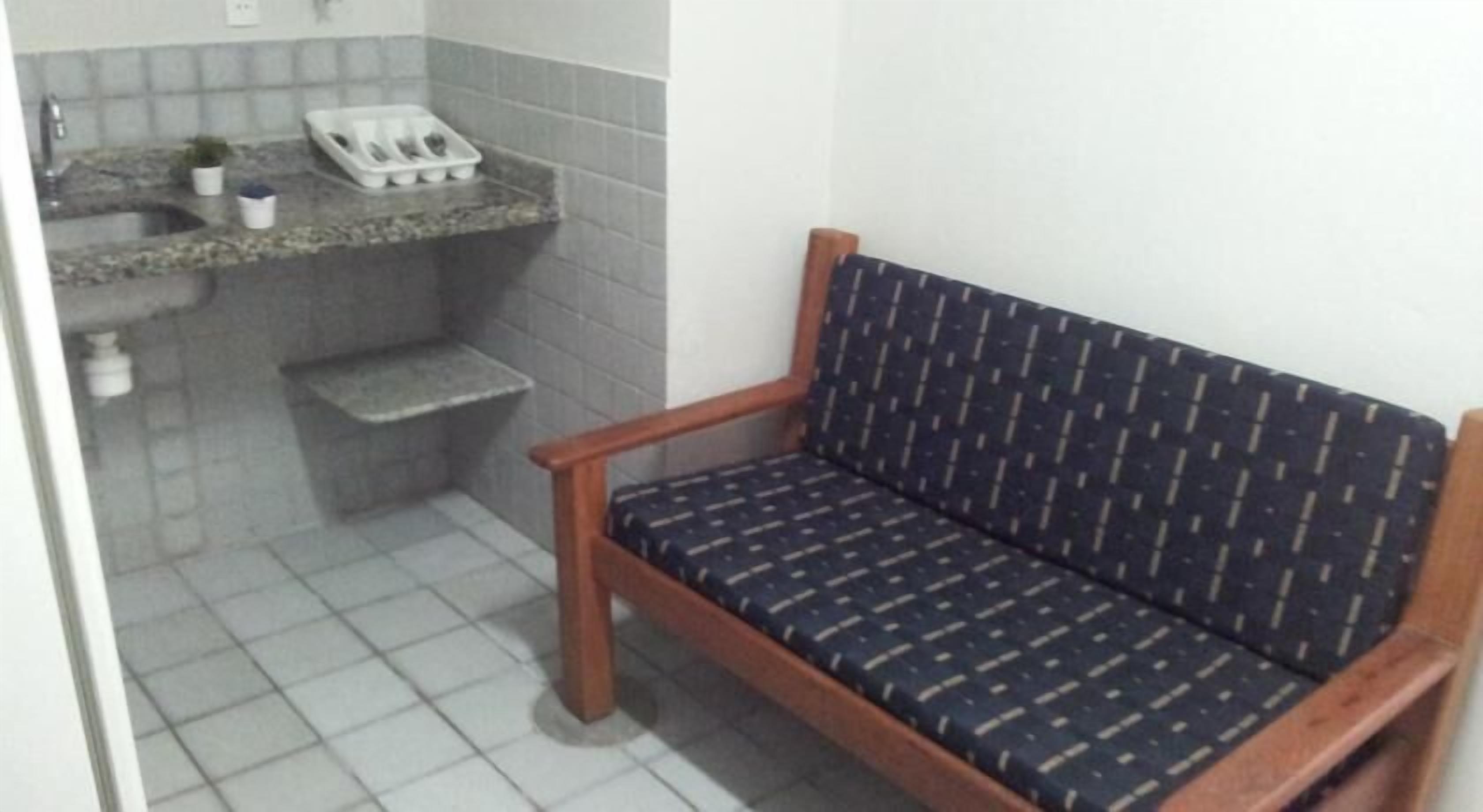 A bathroom with a wooden bench, a sink, and a small shelf with toiletries.