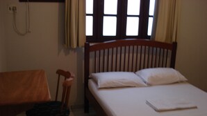 A small, single-bed room with a wooden headboard, a wooden chair, and a window with curtains. - Praia Apart Hotel (Natal)