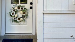 A white door with a frosted glass panel, a wreath, and the number '110' on the wall. - The Woodlands Retreat Getaway & Theater Luxury (The Woodlands)