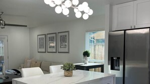A modern kitchen with a marble island, stainless steel appliances, and a pendant light. - The Woodlands Retreat Getaway & Theater Luxury (The Woodlands)
