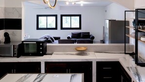 Una cocina moderna con microondas integrado, una cafetera y un bol de madera en la encimera. Dos ventanas ofrecen luz natural y vistas al exterior.