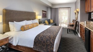 Habitación de hotel con una cama grande, un escritorio, una silla, una mesa de comedor y una zona de cocina.