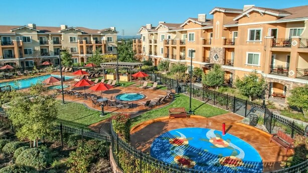 Un hotel de varios pisos con piscina, zona de estar al aire libre y un jardín ajardinado.
