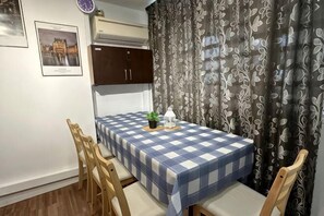 Un coin repas avec une nappe à carreaux, des chaises en bois, une petite plante et une lanterne.