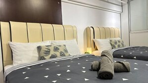 A hotel room with two beds, each with a headboard, pillows, and a rolled towel on the bed. - The CEO SuiteZ1 By Homey Planet (Bayan Lepas)