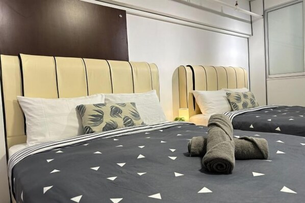 A hotel room with two beds, each with a headboard, pillows, and a rolled towel on the bed. - The CEO SuiteZ1 By Homey Planet (Bayan Lepas)