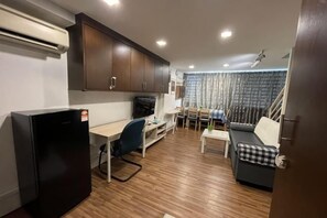 A compact kitchen with a refrigerator, wooden flooring, and a dining area with a table and chairs. - The CEO SuiteZ1 By Homey Planet (Bayan Lepas)