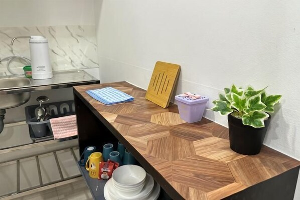 A kitchen counter with a coffee maker, a plant, a framed picture, and a blue notebook. - The CEO SuiteZ1 By Homey Planet (Bayan Lepas)