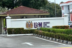 Un edificio con un letrero que dice 'Universiti Sains Malaysia' y un techo de tejas rojas.