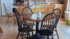 Una cucina con mobili in legno, un tavolo da pranzo con sedie e un frigorifero.
