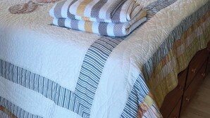 Un letto con una coperta e dei cuscini, un comodino con una lampada e un elemento decorativo a parete.