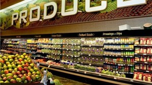 Un supermercado con una sección de frutas y verduras destacada, que exhibe una gran variedad de productos.