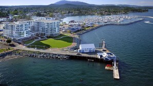Puerto deportivo con barcos, un muelle y un edificio moderno con un césped verde.
