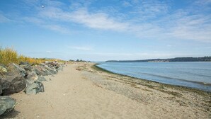 Una playa arenosa con costa rocosa y agua tranquila.