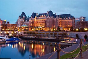 Een groot, historisch hotel met een statig gevelontwerp, een ligging aan het water en een goed verlichte boulevard.