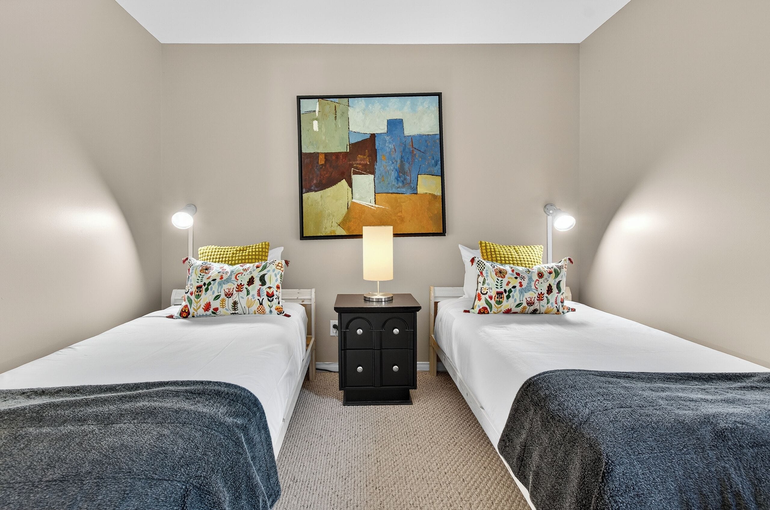A hotel room with two beds, a nightstand with a lamp, and a painting on the wall.