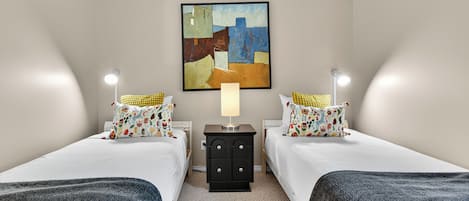A hotel room with two beds, a nightstand with a lamp, and a painting on the wall.
