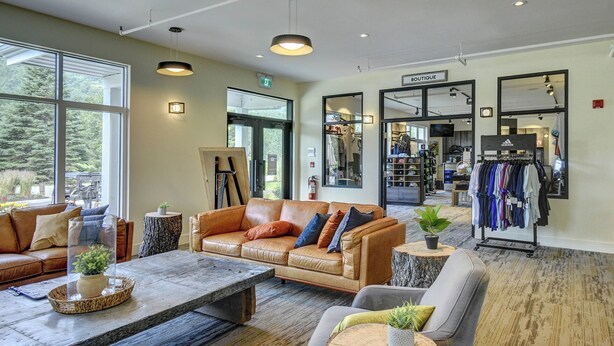A spacious boutique hotel lobby with a leather sofa, a coffee table, and a clothing rack. - 1704 Chemin du Golf (Mont-Tremblant)
