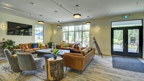 A spacious lobby with a large sofa, chairs, a coffee table, and a painting on the wall. - 1704 Chemin du Golf (Mont-Tremblant)