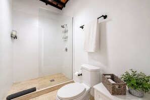 A bathroom with a glass-enclosed shower, a toilet, a sink, a towel rack, and a potted plant. - Big Penthouse 3BR: Walk Everywhere • 3 Balconies • King Beds • Private Patio (San Juan)