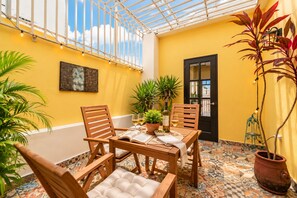 Une terrasse ensoleillée avec une table en bois, des chaises et des plantes en pot.