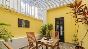 Una habitación con paredes amarillas, una mesa y sillas de madera, una planta en maceta y una puerta.