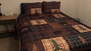 Ein Schlafzimmer mit Bett, Nachttisch, Deckenventilator und einem Bild an der Wand.