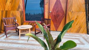 A wooden room with two chairs and a small table, a large window, and a door with a geometric design. - Asia Rainforest Resort (Semporna)