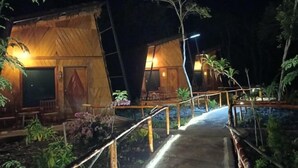 A wooden cabin with a thatched roof, surrounded by a garden with various plants and a paved pathway leading to the entrance. - Asia Rainforest Resort (Semporna)