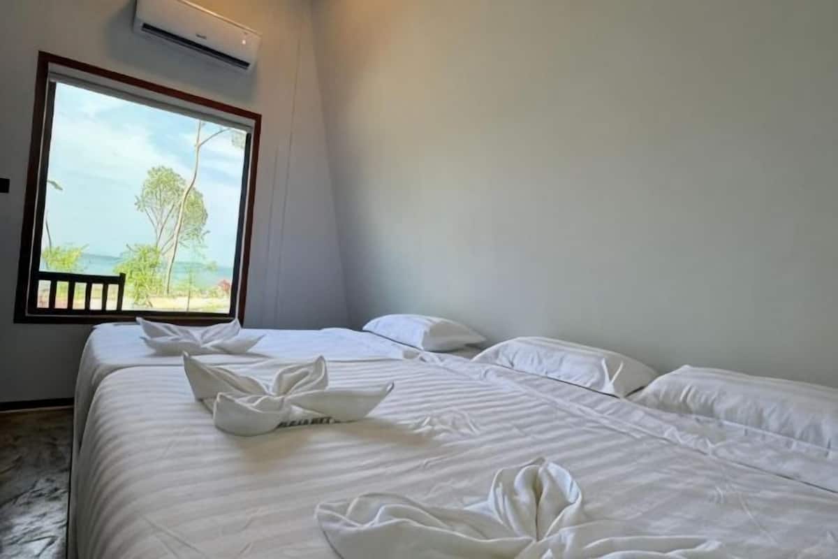 A bedroom with two beds, a large window, and an air conditioning unit.