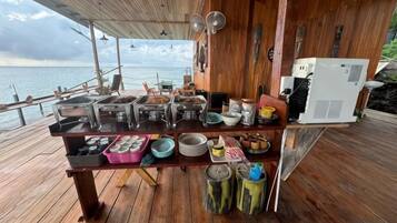 Eine Holzterrasse mit einem Buffet, einem Warmwasserspeicher und Blick aufs Meer.