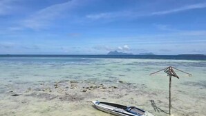 A boat on a clear beach with a clear sky and distant mountains. - Asia Rainforest Resort (Semporna)