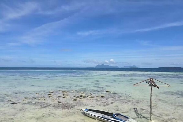 A boat on a clear beach with a clear sky and distant mountains. - Asia Rainforest Resort (Semporna)