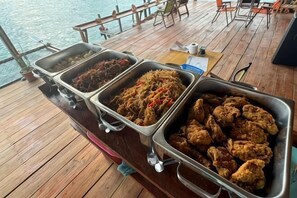 A buffet with various dishes on a wooden deck. - Asia Rainforest Resort (Semporna)