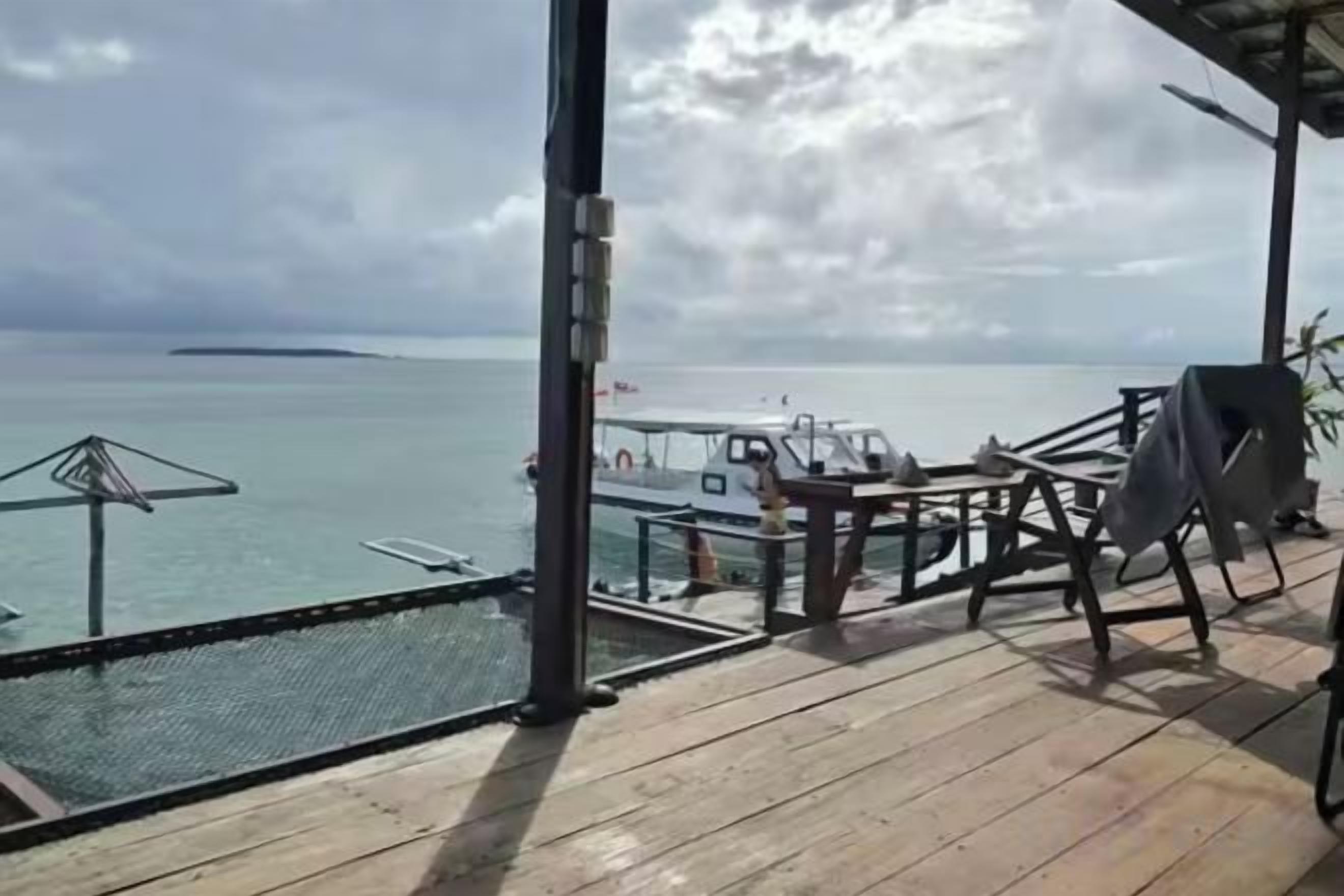 A wooden deck with a view of the sea and a boat.
