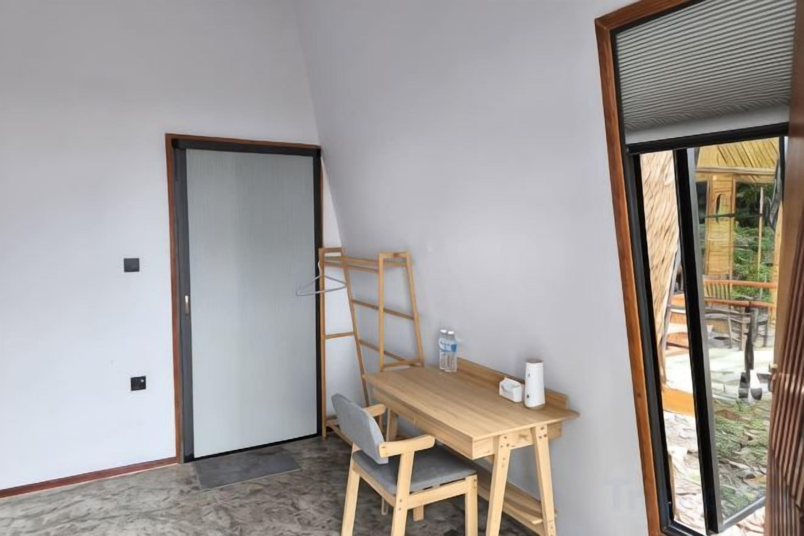 Una habitación con un escritorio de madera, una silla, una mesita y una puerta.