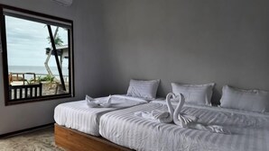 A bed with white linens and two swans, a window with a view of the beach, and a wooden headboard. - Asia Rainforest Resort (Semporna)