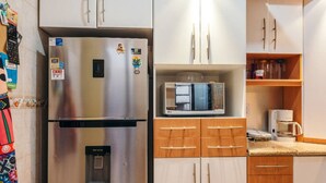 A kitchen with a stainless steel refrigerator, a microwave, wooden cabinets, and a water dispenser.