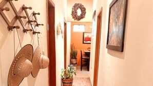 A hallway with a wooden floor, a wall-mounted hat rack, a potted plant, and a framed picture.