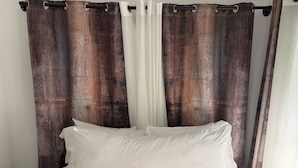 A bed with white bedding, brown curtains, and a wooden headboard. - Studio in vibrant Miami near the ports of Miami. (Miami)