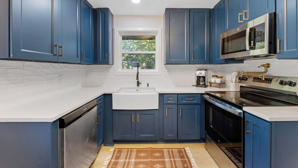 Una cocina moderna con armarios azules, un microondas de acero inoxidable y un horno empotrado.
