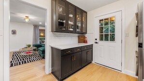 Una cocina moderna con armarios oscuros, encimera blanca y refrigerador de acero inoxidable.