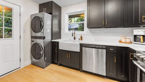 Una cocina moderna con armarios oscuros, electrodomésticos de acero inoxidable y un ventanal que proporciona luz natural.