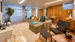 Una sala de estar moderna con un sofá, sillones, una mesa de comedor y una zona de cocina.