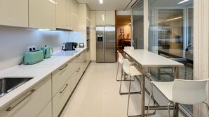 Una cocina moderna con una isla central, electrodomésticos de acero inoxidable y una zona de comedor con taburetes de bar.