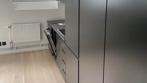 A modern kitchen with a built-in stainless steel refrigerator, a window with blinds, and a white radiator. - Apartment - Sleeps 3 & Great Location (Sollentuna)